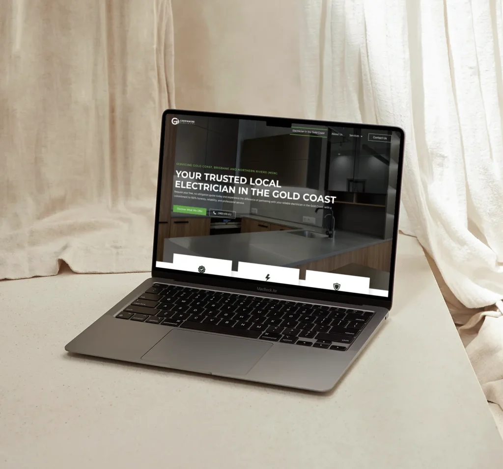 Laptop displaying a website for a local electrician service in the Gold Coast, featuring a modern kitchen background.