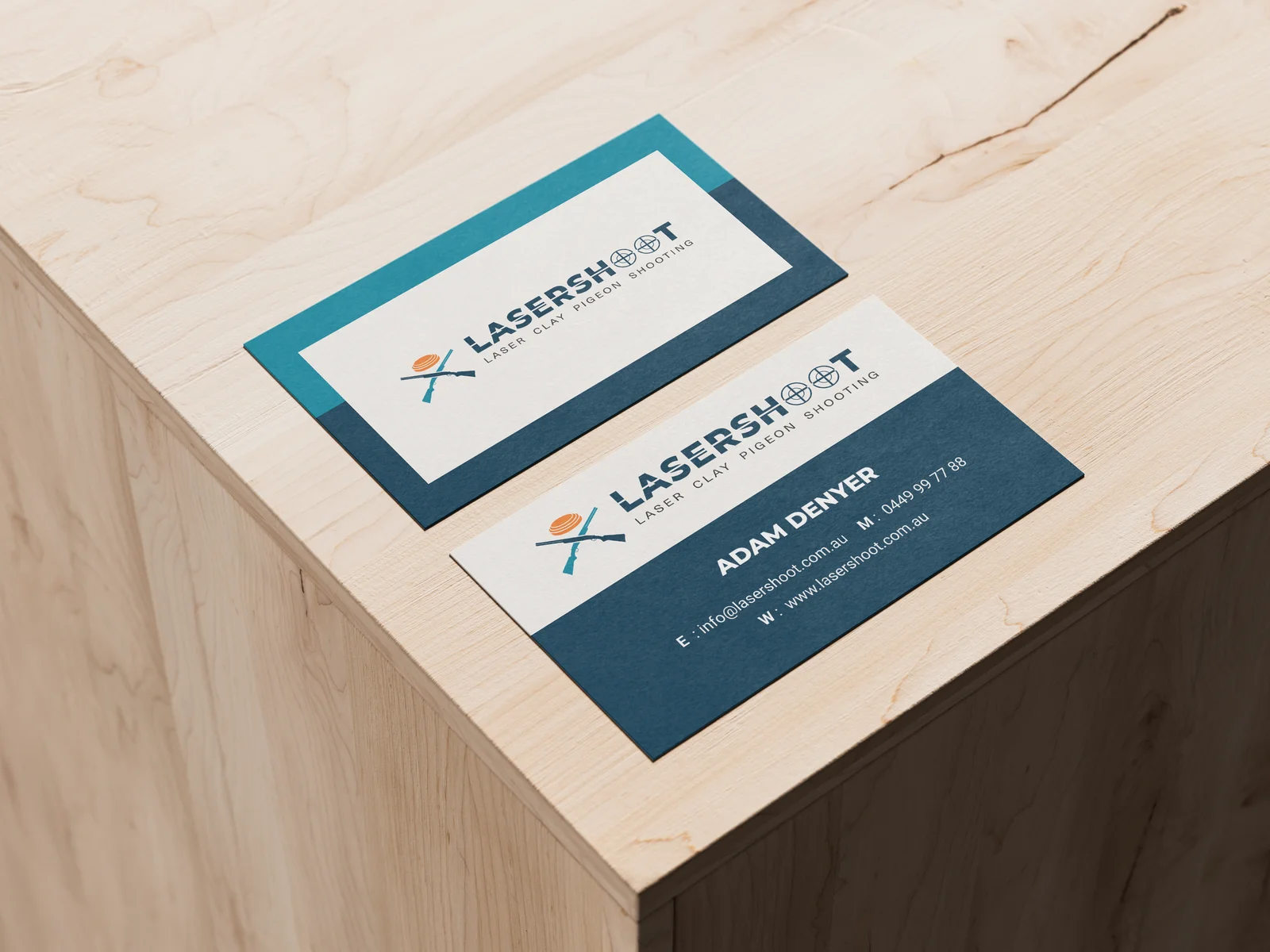 Business cards for Lasershot featuring contact details and logo, displayed on a wooden surface.